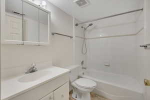 Bathroom with vanity, a textured ceiling, and tub / shower combination