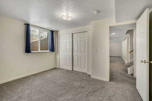 Unfurnished bedroom featuring light colored carpet, a closet, and a textured ceiling