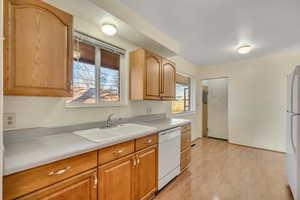 Kitchen with light countertops, white appliances, and light wood-style flooring