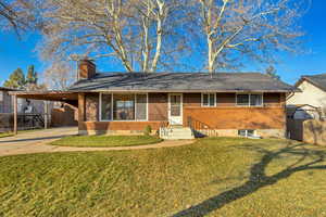 Single story home featuring concrete driveway, a chimney, brick siding, and an attached carport