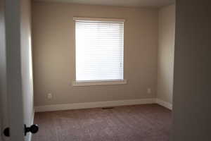 Carpeted empty room featuring baseboards
