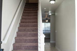Stairs with a ceiling fan and tile patterned floors