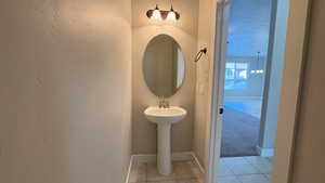 Bathroom with a textured ceiling, light tile patterned floors, and light carpet