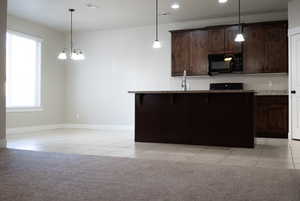 Kitchen featuring decorative light fixtures, a breakfast bar, dark brown cabinets, light tile patterned floors, and recessed lighting