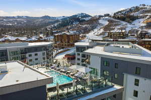 Snowy aerial view with a mountain view and view of pool area