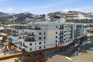 Snow covered building featuring a mountain view and a view of apartment building / complex