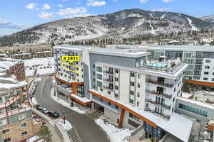 Snowy aerial view with a mountain view and a view of apartment building / complex