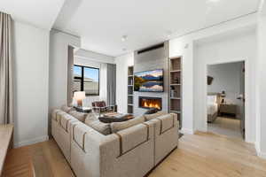 Living area with light wood-type flooring, a tile fireplace, and built in features