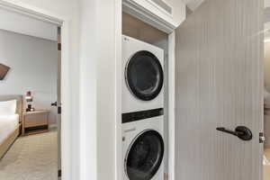 Laundry room featuring stacked washer and clothes dryer and carpet
