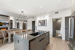 Kitchen with pendant lighting, a kitchen island with sink, modern cabinets, light wood-style floors, and high quality fridge