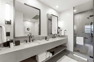 Full bathroom featuring a shower stall, double vanity, and recessed lighting