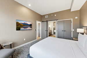 Bedroom featuring a barn door, a closet, and ensuite bathroom