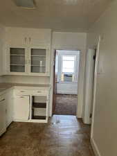 Kitchen featuring white cabinets, tile countertops, and glass insert cabinets