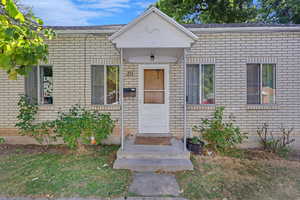 Doorway to property featuring brick siding and a shingled roof