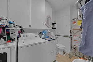 Laundry area with light wood finished floors, water heater, separate washer and dryer, and heating unit