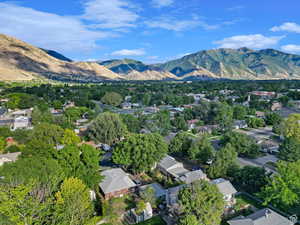 Aerial view of property and surrounding area featuring a mountain backdrop and nearby suburban area
