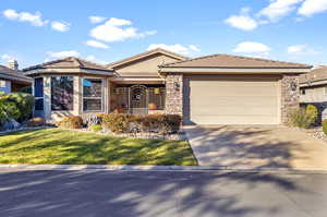 View of front facade featuring stone siding, concrete driveway, and a tiled roof