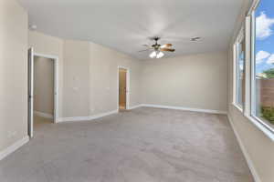 Primary bedroom with light carpet and a ceiling fan