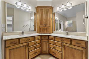 Primary bathroom with double vanity and light tile patterned flooring