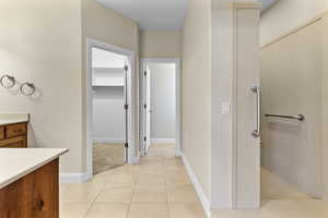 Full Primary bathroom featuring vanity, a walk in closet, light tile patterned floors, and a walk in shower