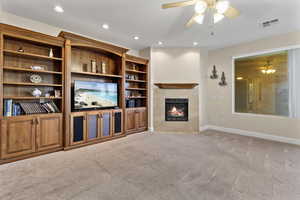 Unfurnished living room with a ceiling fan, light colored carpet, recessed lighting, and a fireplace