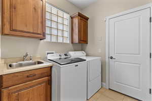 Washroom featuring cabinet space, separate washer and dryer, and light tile patterned floors