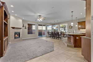 Living room with a tile fireplace, recessed lighting, light tile patterned floors, a chandelier, and a ceiling fan