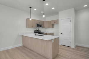 Kitchen with a peninsula, modern cabinets, light wood-style floors, hanging light fixtures, and recessed lighting