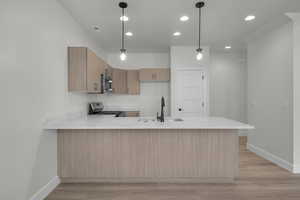 Kitchen with decorative light fixtures, light stone countertops, a peninsula, modern cabinets, and light wood finished floors