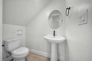 Bathroom with lofted ceiling and wood finished floors