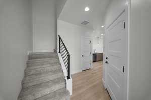 Stairs featuring recessed lighting and wood finished floors