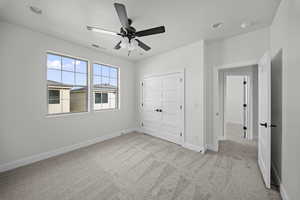 Unfurnished bedroom featuring light colored carpet, a ceiling fan, and a closet