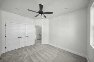 Unfurnished bedroom featuring light colored carpet, a ceiling fan, and a closet