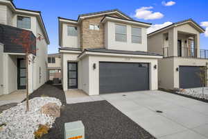 View of front facade featuring stucco siding, stone siding, a tiled roof, a garage, and driveway