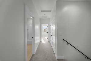 Hall featuring baseboards and light colored carpet