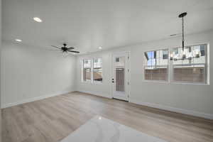 Unfurnished living room featuring recessed lighting, light wood finished floors, a chandelier, and ceiling fan