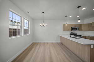 Kitchen featuring modern cabinets, pendant lighting, light stone counters, light wood-style floors, and recessed lighting