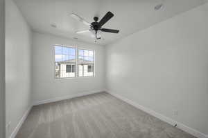 Carpeted empty room with baseboards and a ceiling fan