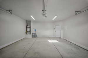 Garage featuring baseboards and water heater