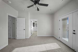 Unfurnished bedroom with ensuite bathroom, light carpet, access to outside, and a ceiling fan