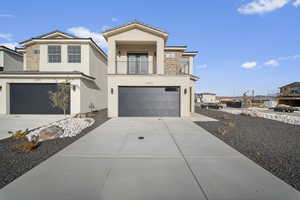 View of front of home with stone siding, stucco siding, a balcony, concrete driveway, and an attached garage