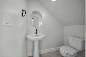 Half bath featuring vaulted ceiling and wood finished floors