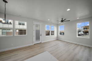 Unfurnished living room with light wood-type flooring, recessed lighting, a chandelier, and a ceiling fan