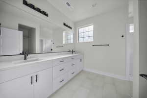 Bathroom with double vanity and baseboards