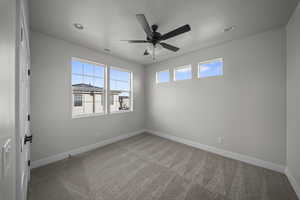 Unfurnished room featuring light colored carpet, plenty of natural light, and ceiling fan