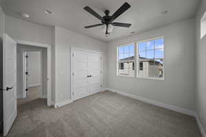 Unfurnished bedroom featuring light carpet, ceiling fan, and a closet