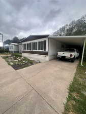 Manufactured / mobile home featuring concrete driveway and an attached carport