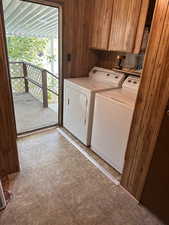 Washroom with cabinet space, wooden walls, and washer and clothes dryer