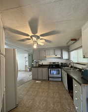 Kitchen with gray cabinetry, stainless steel electric stove, dark countertops, freestanding refrigerator, and ceiling fan