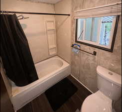 Bathroom with shower / bath combo with shower curtain and dark wood-style floors